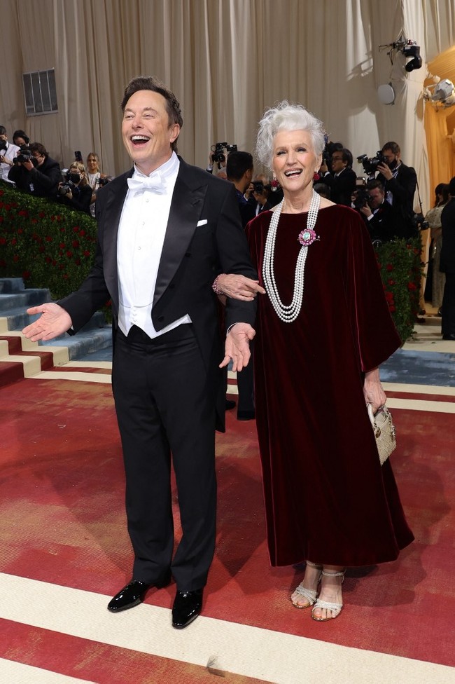 Ditemani ibunya, Maye Musk, Elon Musk menebar senyumannya di Met Gala 2022. Ditanya soal setelan yang dipakainya, begini jawaban Elon, “Hanya mengikuti dress code.” Foto: Getty Images via AFP/MIKE COPPOLA