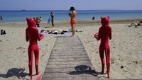 Seorang perempuan tengah melihat telepon genggamnya di pantai den Bossa. Sempat ditutup dua tahun karena pandemi, kini pulau di Spanyol ini telah membuka diri bagi ribuan wisatawan.  