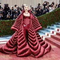 Saat tiba di karpet merah Met Gala 2022, Gigi Hadid menambahkan coat super besar dalam penampilannya. Seluruh busana yang dipakainya ke Met Gala 2022 datang dari brand Versace. Foto: Getty Images via AFP/JAMIE MCCARTHY