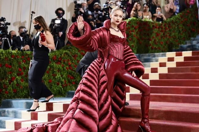 Kakak Bella Hadid itu keluar dari hotel sebelum datang ke Met Gala 2022 dengan catsuit dan korset latex berwarna merah burgundy. Penampilannya sungguh memesona ditambah dengan lipstik merah menyala yang senada dengan busananya. Foto: Getty Images via AFP/JAMIE MCCARTHY