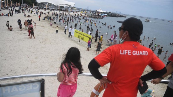 Petugas memantau pengunjung dalam upaya membantu seorang anak menemukan orang tuanya di kawasan Pantai Ancol.