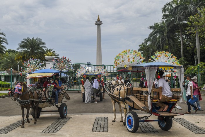 Warga naik delman di kawasan luar Monumen Nasional (Monas), Jakarta, Selasa (3/5/2022). Meski kawasan Monas masih ditutup sejak awal pandemi COVID-19 pada Maret 2020 lalu namun tidak menyurutkan minat warga untuk bisa berwisata yaitu dengan memanfaatkan kawasan luar monumen tersebut. ANTARA FOTO/Galih Pradipta/nym.
