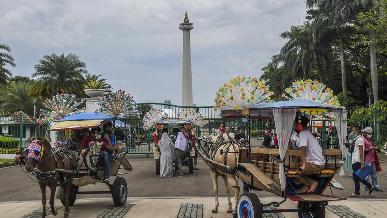 Warga naik delman di kawasan luar Monumen Nasional (Monas), Jakarta, Selasa (3/5/2022). Meski kawasan Monas masih ditutup sejak awal pandemi COVID-19 pada Maret 2020 lalu namun tidak menyurutkan minat warga untuk bisa berwisata yaitu dengan memanfaatkan kawasan luar monumen tersebut. ANTARA FOTO/Galih Pradipta/nym.
