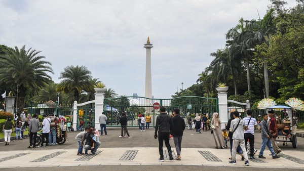 Warga bersantai hingga berfoto di kawasan luar Monumen Nasional (Monas) Jakarta, Selasa (3/5/2022).