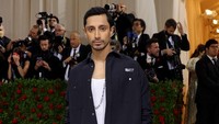 Penampilan kasual Riz Ahmed dilengkapi dengan kalung panjnag menjuntai hingga ke bagian bawah dada. (Foto: Getty Images via AFP/JAMIE MCCARTHY) 