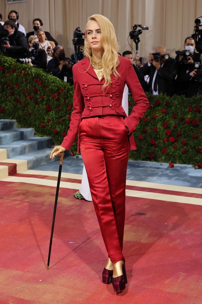 Setelan merah dari Dior Haute Coutre dengan blazer bertema militer membungkus tubuh model dan aktris 29 tahun itu. Ia lalu melengkapi gayanya dengan platform heels dan tongkat. (Foto: Getty Images via AFP/DIMITRIOS KAMBOURIS)