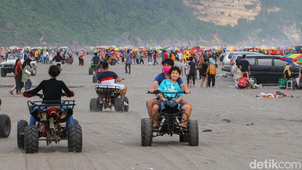 Pengunjung bermain motor roda empat di pantai Parangtritis.