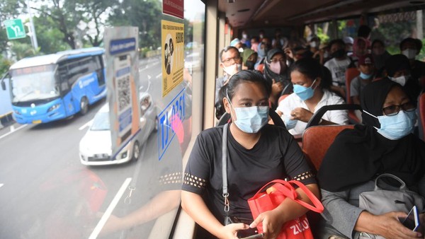 Warga duduk di dalam bus wisata gratis. Meski ramai warga tetap mentaati protokol kesehatan seperti memakai masker.