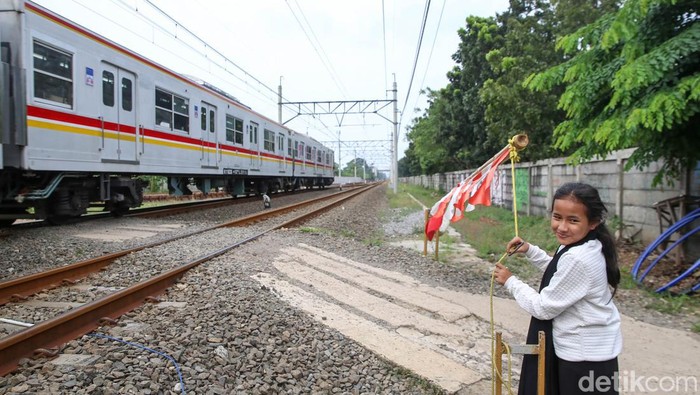 Khofifah dan Adiknya Lala, menjaga palang pintu perlintasan kereta api di kawasan Poris, Tangerang, Rabu (4/5/2022). Khofifah dan Lala kerap membantu menjaga palang perlintasan pintu kereta api ketika ayahnya atau penjaga lainnya sedang beristirahat atau berhalangan menjaga palang pintu perlintasan tersebut.