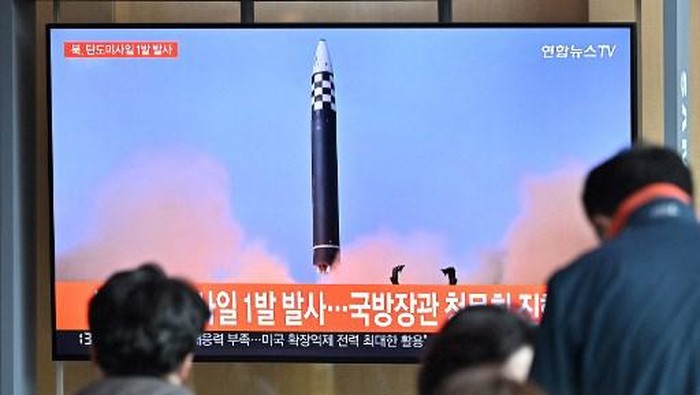 People watch a television screen showing a news broadcast with file footage of a North Korean missile test, at a railway station in Seoul on May 4, 2022. - North Korea fired a ballistic missile on May 4, South Koreas military said, just a week after leader Kim Jong Un vowed to boost Pyongyangs nuclear arsenal at the 