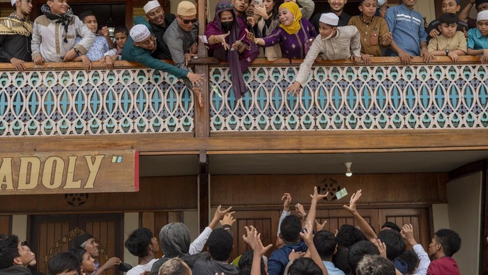 TRADISI LEBARAN ARAB DI PALU Sejumlah warga berebut uang yang dibagikan pada tradisi Lebaran Arab atau Iwwadh di Palu, Sulawesi Tengah, Selasa (3/5/2022). Tradisi yang telah diwarisi sejak puluhan tahun lalu itu digelar oleh warga muslim keturunan Arab yang tinggal di Palu dan biasanya dilakukan setiap hari kedua Idul Fitri dengan bersilaturahim dari rumah ke rumah untuk mendoakan pemilik rumah serta membagi-bagikan uang. ANTARA FOTO/Basri Marzuki/nym.