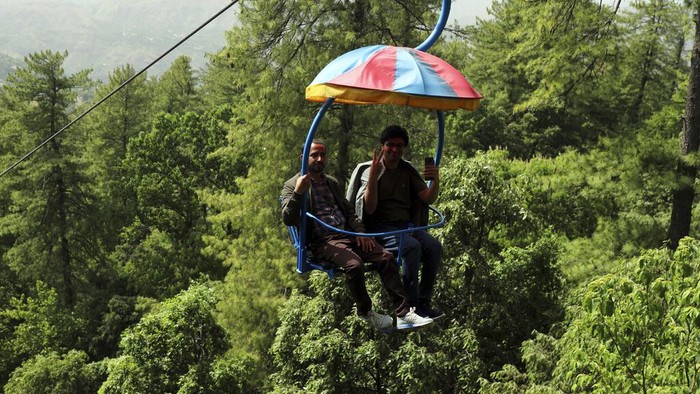 Warga Pakistan Rayakan Libur Lebaran Naik Kursi Gantung Tourists enjoy riding chairlifts at the hill resort town of Murree, during the first day of Eid al-Fitr near Islamabad, Pakistan, Tuesday, May 3, 2022. (AP Photo/Rahmat Gul)