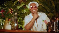 Sambil mengenakan kacamata begitu kaya Anderson .Paak saat menikmati racikan minuman favoritnya. Minumannya dihias dengan payung kecil di gelasnya. Foto: Getty Images