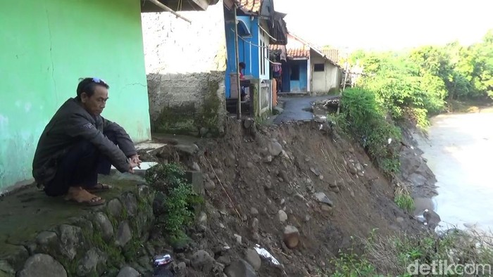 Warga di antara tebing yang longsor akibat tergerus luapan Sungai Cibimbin