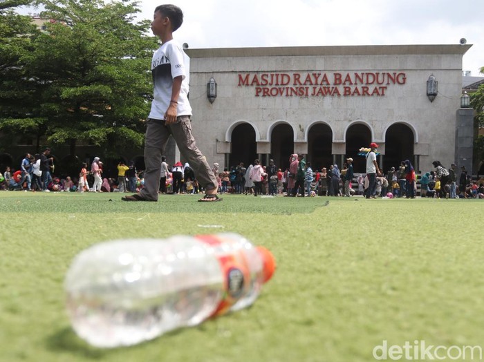 Warga masih menggunakan alas kaki saat menginjak rumput sintetis di Alun-alun Kota Bandung