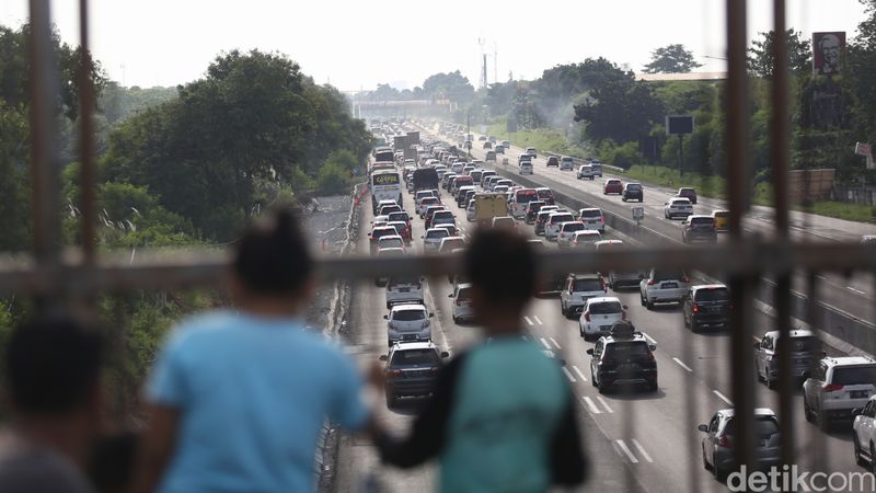 Sejumlah warga menonton kemacetan yang terjadi di ruas Tol Cikampek arah Jakarta saat pemberlakuan one way. Aksi itu dilakukan untuk membagikan informasi ke temannya yang mudik lewat grup WhatsApp (WA), Jumat, (6/5/2022).