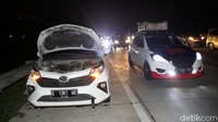Sebuah mobil nampak mengalami masalah dan berhenti di bahu jalan.