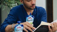 Refal menikmati yogurt saat membaca buku. Yogurt yang asam manis segar ini tampak dinikmati sekali oleh Refal Hady. Foto: Instagram @refalhady