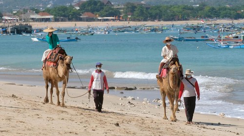 Wisatawan menikmati suasana pantai dengan menaiki unta saat liburan di Pantai Kelan, Badung, Bali, Sabtu (7/5/2022). Penyewaan wahana unta di objek wisata tersebut mengalami peningkatan pada saat liburan Lebaran dengan harga sewa Rp 150 ribu hingga Rp 200 ribu sesuai durasi yang telah ditentukan. ANTARA FOTO/Nyoman Hendra Wibowo/tom.