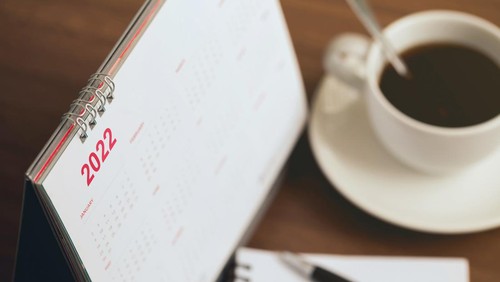 Happy new year 2022 concept.Close up Calendar 2022 schedule with cup of coffee and blank note for to do list on wooden desk.Starting the new year and planning for the future
