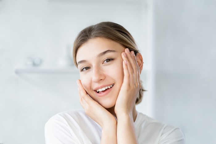 Ilustrasi Skincare Remaja Natural beauty. Healthy skin. Dermatology hygiene. Cheerful smiling woman touching healthy fresh face on light defocused bathroom at morning.