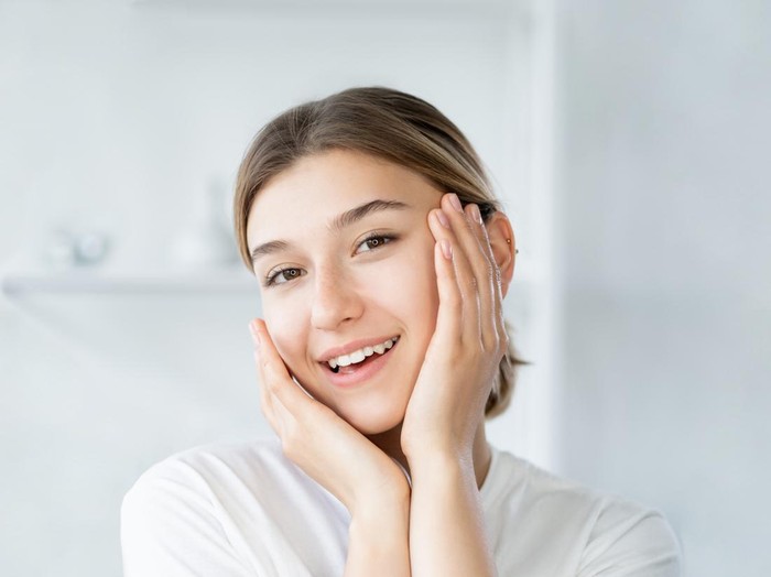 Ilustrasi Skincare Remaja Natural beauty. Healthy skin. Dermatology hygiene. Cheerful smiling woman touching healthy fresh face on light defocused bathroom at morning.