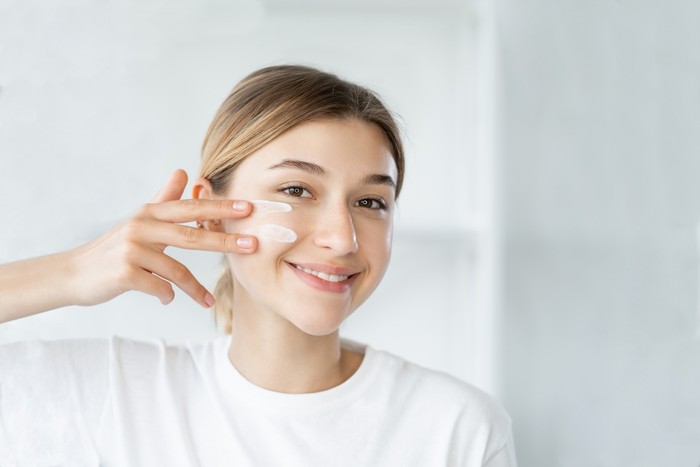 Natural beauty. Healthy skin. Dermatology hygiene. Cheerful smiling woman touching healthy fresh face on light defocused bathroom at morning.