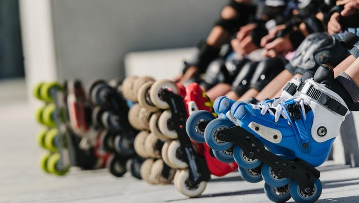 Feet of rollerbladers wearing inline roller skates sitting in outdoor skate park, Close up view of wheels befor city race for healthy and active life