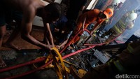 Petugas pemadam kebakaran tampak dibantu warga setempat saat berupaya memadamkan kebakaran.