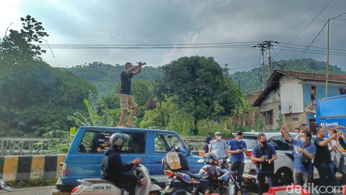 Pengendara berjoget di atas mobil.