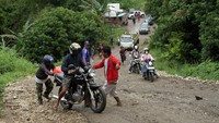 Warga membantu pengendara saat melintas di jalan poros Enrekang-Pinrang yang rusak parah di Kecamatan Cendana, Kabupaten Enrekang, Sulawesi Selatan, Minggu (8/5/2022).