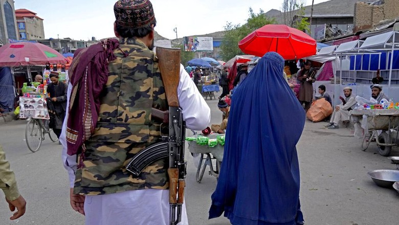 A woman wearing a burka walks through a bird market as she holds her child, in downtown Kabul, Afghanistan, Sunday, May 8, 2022. Afghanistan’s Taliban rulers on Saturday ordered all Afghan women to wear head-to-toe clothing in public — a sharp, hard-line pivot that confirmed the worst fears of rights activists and was bound to further complicate Taliban dealings with an already distrustful international community. (AP Photo/Ebrahim Noroozi)