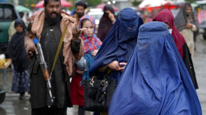 A woman wearing a burka walks through a bird market as she holds her child, in downtown Kabul, Afghanistan, Sunday, May 8, 2022. Afghanistan’s Taliban rulers on Saturday ordered all Afghan women to wear head-to-toe clothing in public — a sharp, hard-line pivot that confirmed the worst fears of rights activists and was bound to further complicate Taliban dealings with an already distrustful international community. (AP Photo/Ebrahim Noroozi)