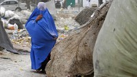 Seorang wanita memakai burqa berjalan di depan rumahnya di Kabul Afghanistan, Minggu (8/5) waktu setempat.  