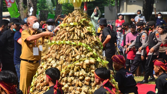 Bupati Jepara Dian Kristiandi (kiri) memotong kupat saat festival kupat lepet di kawasan wisata Pantai Kartini, Jepara, Jawa Tengah, Senin (9/5/2022). Festival yang diadakan sepekan setelah Idul Fitri dengan berebut gunungan berisi makanan kupat dan lepet yang sudah didoakan itu sebagai simbol saling memaafkan kesalahan antarsesama setelah Lebaran. ANTARA FOTO/Yusuf Nugroho/rwa.