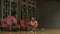 Warga duduk di depan rumahnya yang terendam banjir di Kampung Baru, Palu, Sulawesi Tengah, Selasa (10/5/2022).