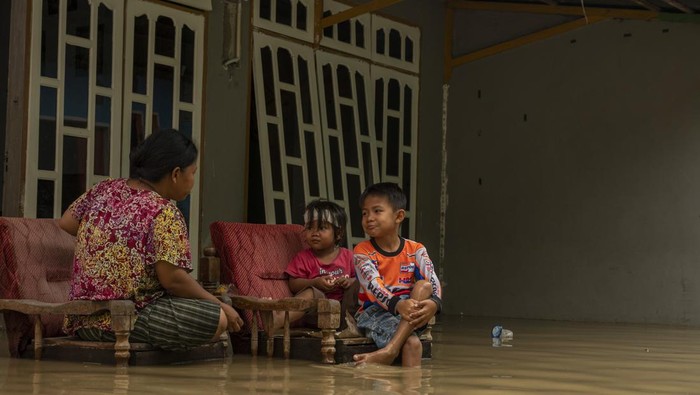 200 Rumah Terdampak Banjir di Palu Warga memangku bayinya di depan rumahnya yang digenangi banjir di Kampung Baru, Palu, Sulawesi Tengah, Selasa (10/5/2022). Banjir yang disebabkan luapan air sungai akibat hujan di hulu itu merendam sedikitnya 200 rumah warga di empat kelurahan dan membuat sejumlah warga terpaksa harus mengungsi. ANTARA FOTO/Basri Marzuki/rwa.