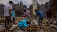 Pranav Mishra (19), berlutut di depan jenazah ibunya Mamta Mishra (45), yang meninggal karena penyakit virus corona, menjelang kremasinya, di New Delhi, India, 4 Mei 2021. REUTERS/Danish Siddiqui