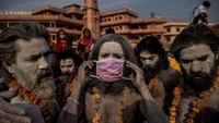 Seorang Naga Sadhu, atau orang suci Hindu, memasang masker di wajahnya sebelum memasuki sungai Gangga selama Shahi Snan tradisional, atau saus kerajaan, di festival Kumbh Mela di Haridwar, India, 12 April 2021. Kasus COVID- 19 membuat kematian meledak di India pada bulan April dan Mei, rumah sakit kehabisan oksigen sehingga banyak pasien mati lemas. REUTERS/Danish Siddiqui