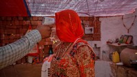 Seorang petugas kesehatan memeriksa suhu tubuh seorang wanita di dalam gubuknya selama upaya vaksinasi penyakit virus corona untuk para pekerja di tempat pembakaran batu bata di desa Kavitha di pinggiran Ahmedabad, India, 8 April 2021. Pulitzer adalah penghargaan paling bergengsi dalam jurnalisme AS, dengan perhatian khusus yang diberikan pada layanan publik. REUTERS/Amit Dave