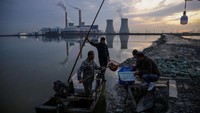 Nelayan di China tengah membawa hasil tangkapan mereka dari danau di depan pembangkit listrik di kawasan Tianjin. REUTERS/Tomas Peter.