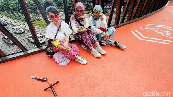 Mereka sepertinya tak merasakan terik sinar matahari saat berselfie di atas JPO Pinisi Sudirman, Jakarta Pusat.