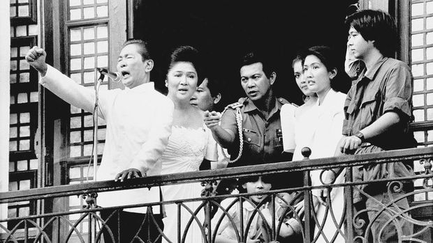 FILE - Ferdinand Marcos, with his wife Imelda at his side and Ferdinand Marcos Jr., far right, gestures strongly from the balcony of Malacanang Palace on Feb. 25, 1986 in Manila, just after taking the oath of office as president of the Philippines. Marcos Jr., son of the late dictator and his running mate Sara, who is the daughter of the outgoing President Rodrigo Duterte, are leading pre-election surveys despite his family's history. (AP Photo/Bullit Marquez, File)