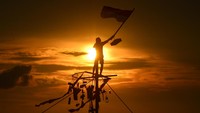 Warga yang sampai di pucuk pinang mengibarkan bendera merah putih. 