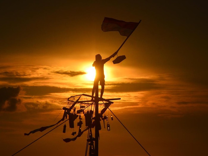 Warga mengibarkan bendera merah putih saat mengikuti lomba Panjat Pinang di kawasan Pantai Kelurahan Demaan, Jepara, Jawa Tengah, Senin (9/5/2022). Panjat Pinang tersebut untuk memeriahkan tradisi Syawalan atau Lebaran ketupat serta untuk menjalin kebersamaan dan menghibur warga. ANTARA FOTO/Yusuf Nugroho/pras.