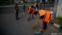 Sejumlah warga menyapu jalanan usai terjaring razia masker di depan Stasiun Klender, Jakarta, Selasa (10/5/2022).