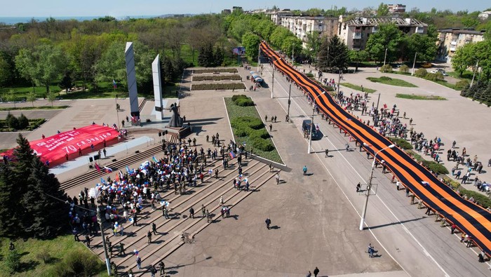Warga Pro-Rusia Merayakan Hari Kemenangan di Mariupol Participants hold a giant St. George's Ribbon during a ceremony, marking the 77th anniversary of the victory over Nazi Germany in World War Two, in the course of Ukraine-Russia conflict in the southern port city of Mariupol, Ukraine May 9, 2022. Picture taken with a drone. REUTERS/Pavel Klimov