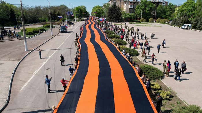 Participants hold a giant St. George's Ribbon during a ceremony, marking the 77th anniversary of the victory over Nazi Germany in World War Two, in the course of Ukraine-Russia conflict in the southern port city of Mariupol, Ukraine May 9, 2022. Picture taken with a drone. REUTERS/Pavel Klimov