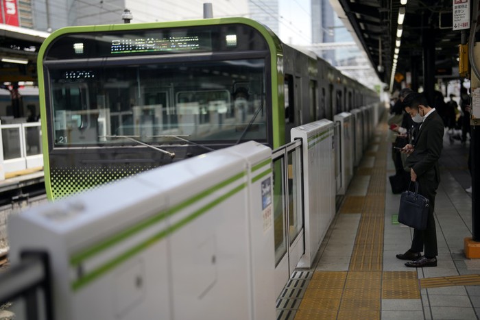 A man wearing a protective mask to help curb the spread of the coronavirus stands at a train station platform Tuesday, May 10, 2022, in Tokyo.   (AP Photo/Eugene Hoshiko)