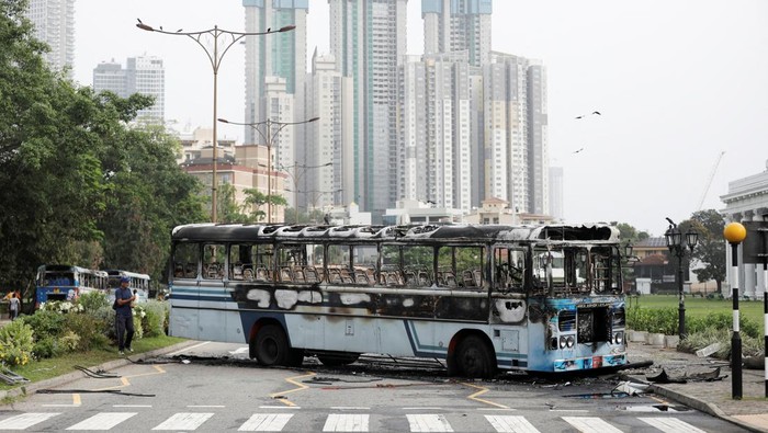 An air force personnel stands guard at a check point near a damaged bus of Sri Lanka's ruling party supporters after it was set on fire during a clash of pro and anti-government demonstrators near the Prime Minister's official residence, amid the country's economic crisis, in Colombo, Sri Lanka, May 10, 2022. REUTERS/Dinuka Liyanawatte